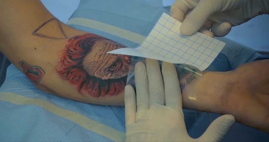 4.Sejměte zadní oanný povlak na delší straně fólie, tak aby ležela celá fólie na tetování
